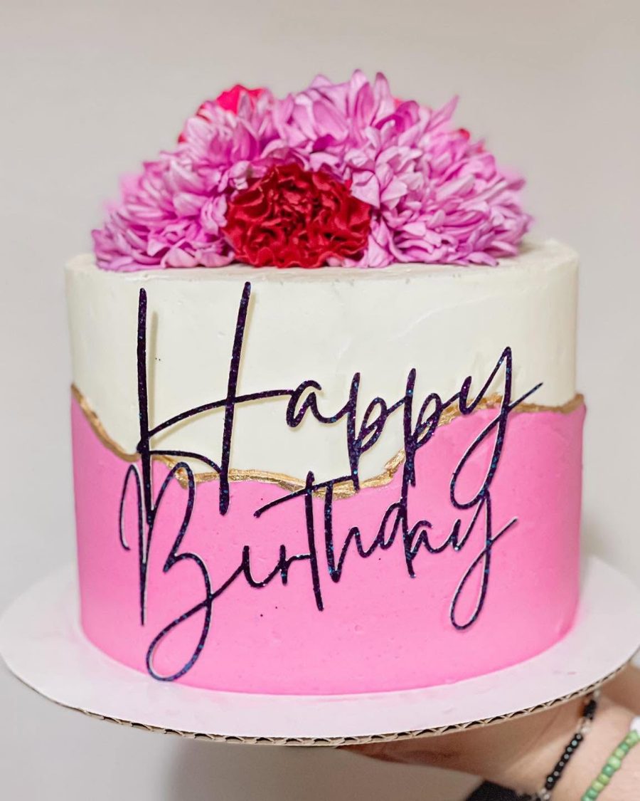 Cakes & Bakes's own photograph: a pink and white birthday cake crowned with magenta blooms.